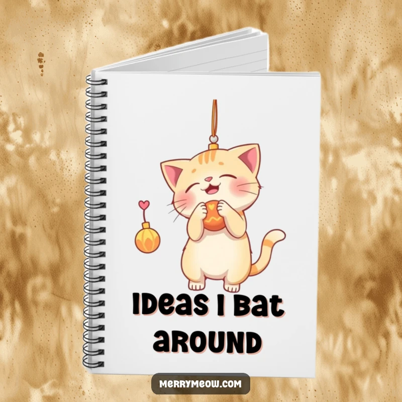 Funny notebook cover with a playful cat batting at a shiny ornament, ideal for capturing notes and holiday-themed musings.