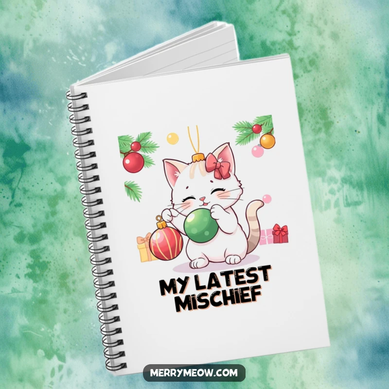 Funny cat character playfully batting a Christmas ornament, featured on the cover of a festive notebook.