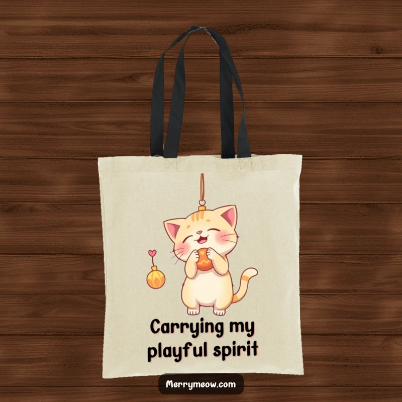 Funny tote bag featuring a playful cat swatting at a dangling holiday ornament, perfect for grocery runs and festive outings.